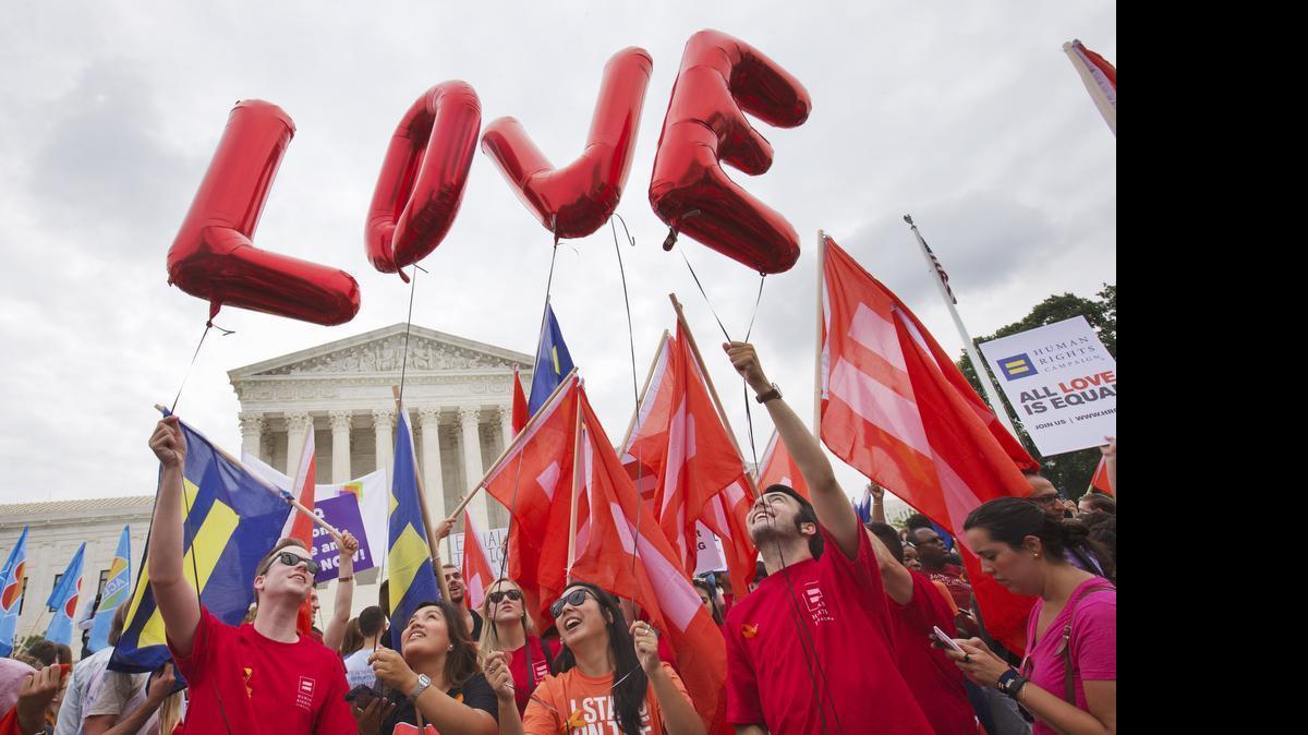 
Same-sex marriage supporters hold up balloons that spell the word "love" as they wait outside of the Supreme Court in Washington, Friday June 26, 2015, before the court declared that same-sex couples have a right to marry anywhere in the US.
