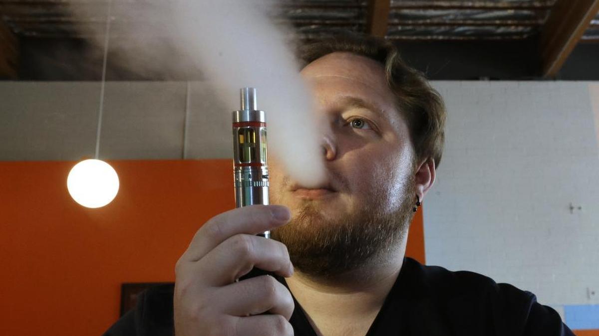 Bruce Schillin, 32, exhales vapor from an e-cigarette at the Vapor Spot, in Sacramento, Calif., last July California’s Senate on Thursday, March 10, 2016, approved a package of anti-smoking measures that include raising the smoking age to 21 and to regulate electronic cigarettes as tobacco, setting restrictions on their use.