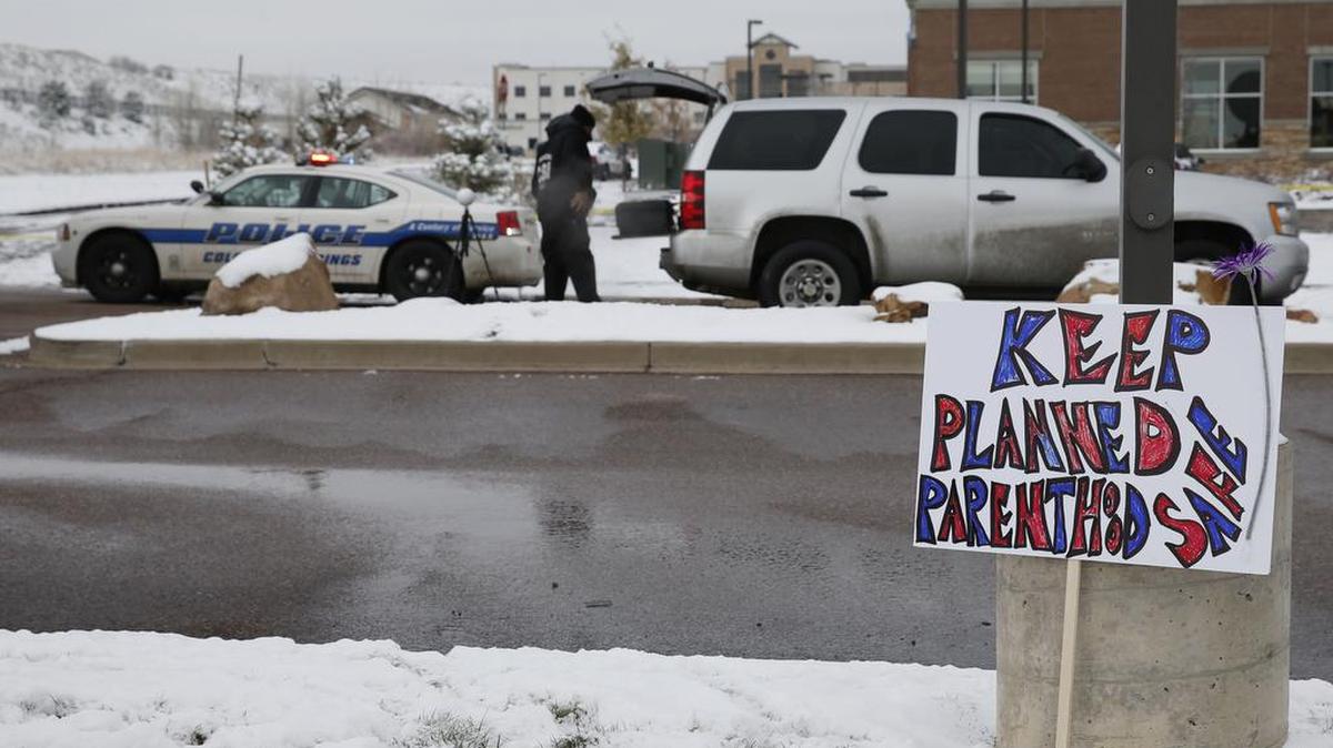 A sign in support of Planned Parenthood stands just south of the clinic as police investigators gather evidence Sunday near the scene of Friday's shooting at the clinic in northwest Colorado Springs, Colo. Bulletproof glass and armed security are nothing new at medical clinics that provide abortions. But in the wake of a deadly shooting last week at a Planned Parenthood clinic in Colorado, clinics nationwide are redoubling security efforts, checking surveillance cameras and reviewing evacuation plans.