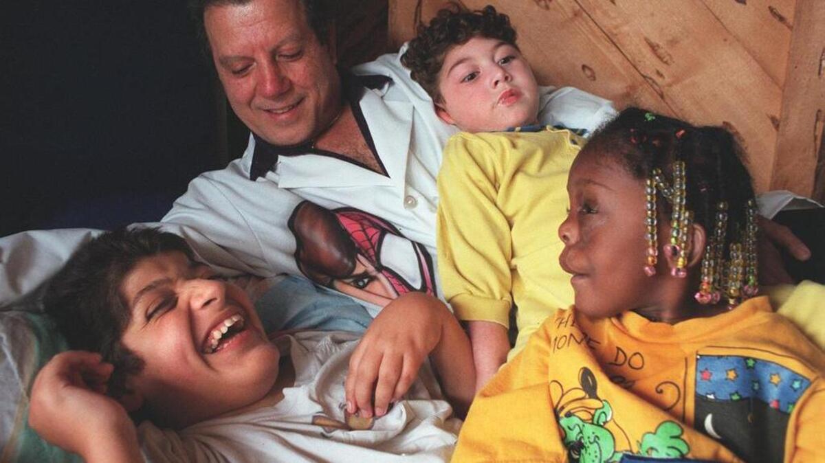 Dr. Michael Geraldi, at home with a few of his children, then numbering more than 40 in November 1996. At left was Jose, then 12, Adam, then 4, Meredith, then 3-1/2. The Geraldi's, for years, have been the home for many children with acute physical problems.