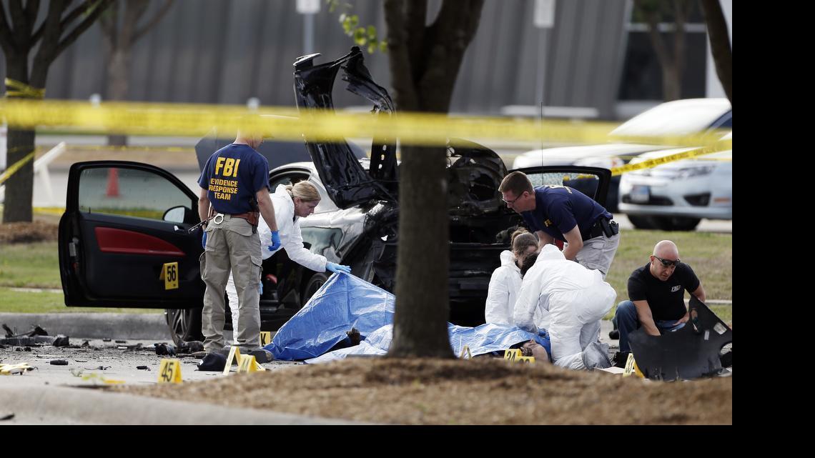 
FBI crime scene investigators document the area around two deceased gunmen and their vehicle outside the Curtis Culwell Center in Garland, Texas, Monday, May 4, 2015. Police shot and killed the men after they opened fire on a security officer outside the suburban Dallas venue, which was hosting provocative contest for Prophet Muhammad cartoons Sunday night. 
