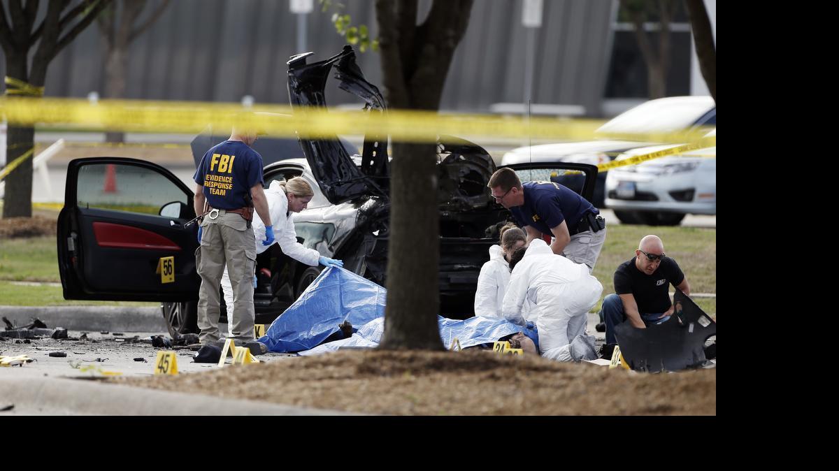 
FBI crime scene investigators document the area around two deceased gunmen and their vehicle outside the Curtis Culwell Center in Garland, Texas, Monday, May 4, 2015. Police shot and killed the men after they opened fire on a security officer outside the suburban Dallas venue, which was hosting provocative contest for Prophet Muhammad cartoons Sunday night. 
