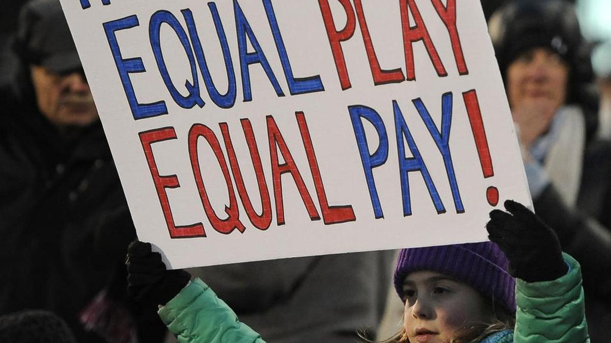 A girl holds up a sign for equal pay for the U.S. women soccer players.