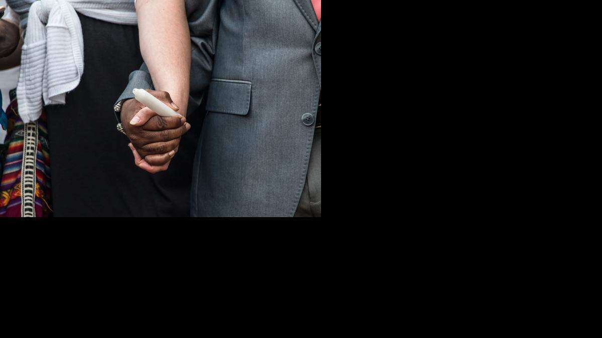 
Two people hold hands during a candlelight vigil for Walter Scott in North Charleston, S.C. on Friday, April 10, 2015. On Saturday, Scott was killed by a police officer after a traffic stop. Officer Michael Slager has been fired and charged with murder. 
