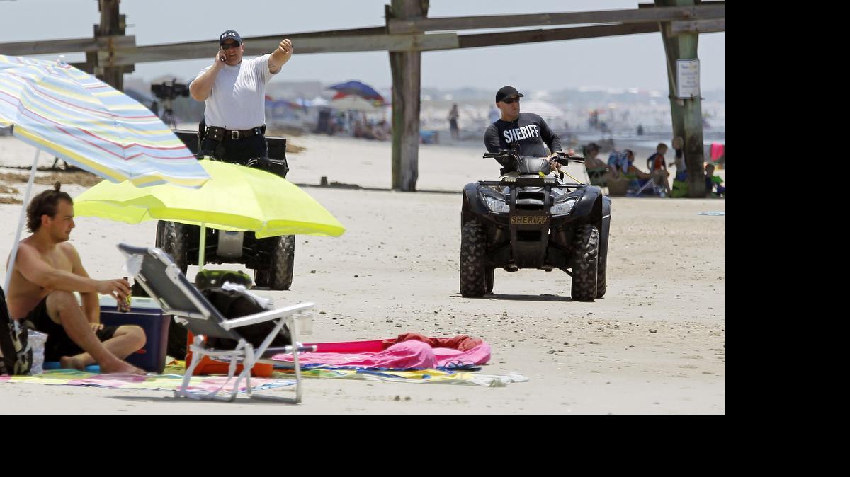 
Members of the Sheriff's department use ATVs to patrol the beach on Oak Island beach near the Ocean Crest Pier as life resumes here on Monday, June 15, 2015. On Sunday, two people were attacked by sharks while swimming in this southeastern North Carolina town. One of the attacks several hundreds yards from here on the other side of the pier. On Monday, a few people went into the water, but not very far out. Most were either on the sand or just in the surf where the water was only a foot or two deep. 
