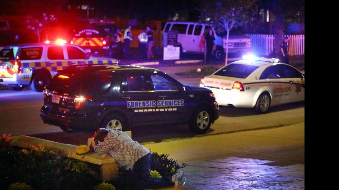 
A man kneels across the street from where police gather outside the Emanuel AME Church following a shooting June 17, 2015, in Charleston, S.C.
