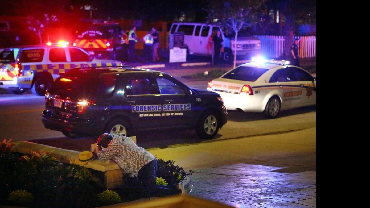 
A man kneels across the street from where police gather outside the Emanuel AME Church following a shooting June 17, 2015, in Charleston, S.C.
