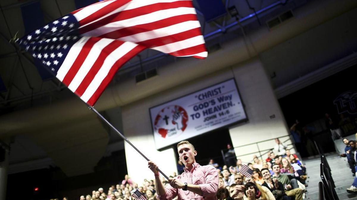 An attendee waves an American flag as Sen. Ted Cruz, R-Texas, speaks at Liberty University in Lynchburg, Va., in March. Students at the university were urged Friday by school President Jerry Falwell Jr. to get a permit to carry a concealed weapon on campus to counter any copycat attack like the deadly rampage in California just days ago.