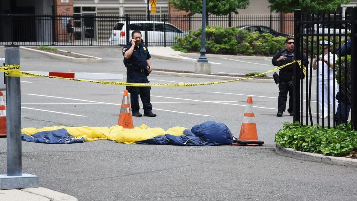 In this Sunday, May 28, 2017 photo, officials surround a U.S. Navy SEAL’s parachute that landed in a parking lot after failing to open. The parachutist died in a Fleet Week demonstration over the Hudson Riverin Jersey City, N.J.