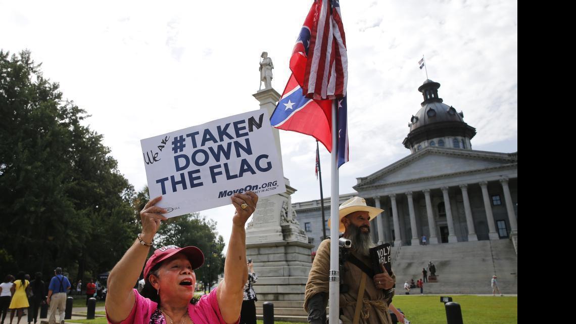 
Maria Calef, of Columbia, S.C., waves a sign as she celebrates in front of the South Carolina statehouse, Thursday, July 9, 2015, in Columbia, S.C. More than 50 years after South Carolina raised a Confederate flag at its Statehouse to protest the civil rights movement, the rebel banner is scheduled to be removed Friday morning during a ceremony.
