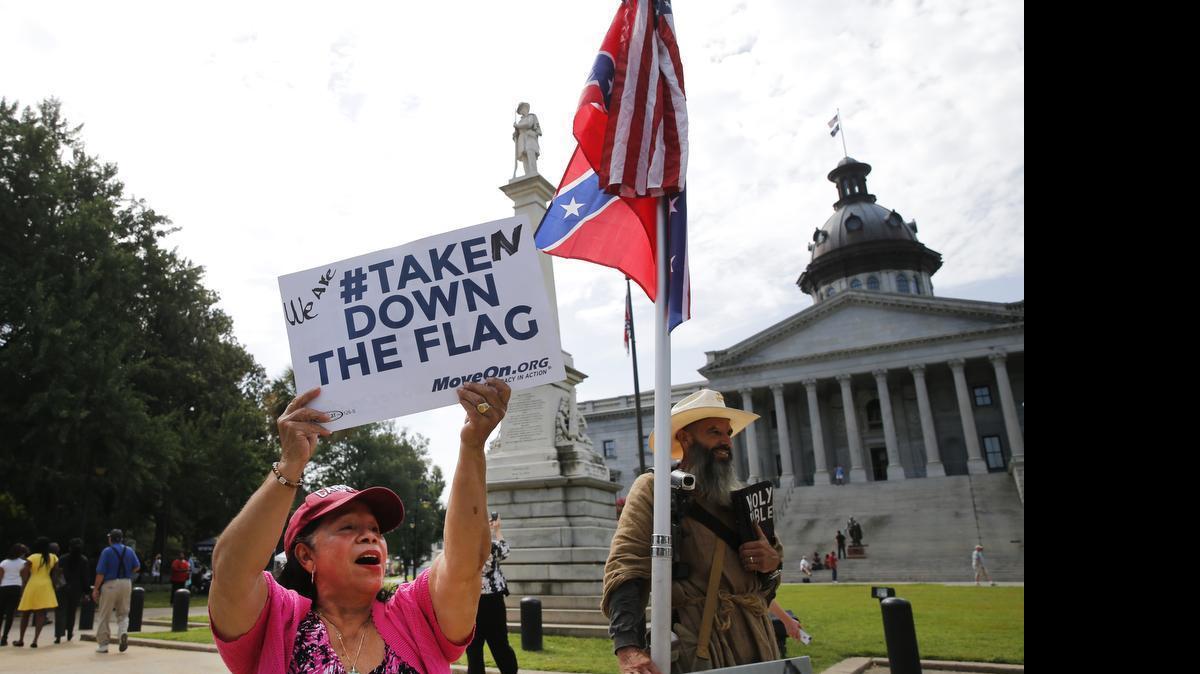 
Maria Calef, of Columbia, S.C., waves a sign as she celebrates in front of the South Carolina statehouse, Thursday, July 9, 2015, in Columbia, S.C. More than 50 years after South Carolina raised a Confederate flag at its Statehouse to protest the civil rights movement, the rebel banner is scheduled to be removed Friday morning during a ceremony.
