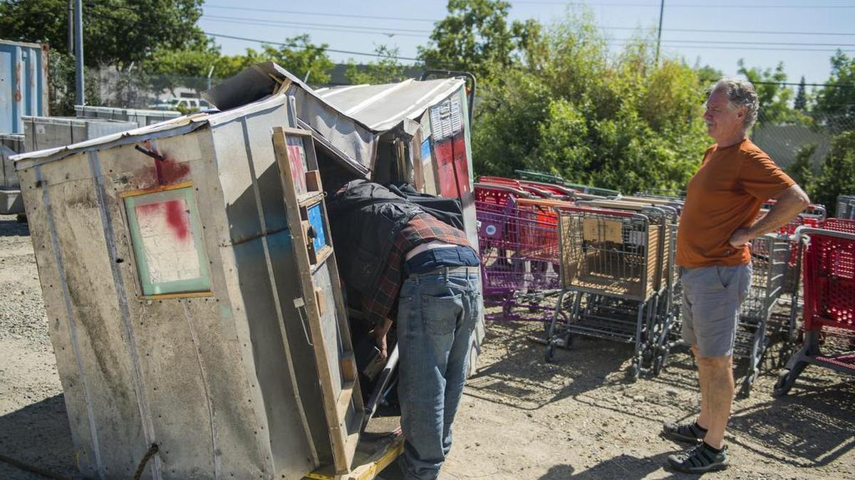Thomas Mullen looks into his "pod" home as his father, Jim, stands back looking at the damage to the pod on Thursday July 20, 2017, in Sacramento, Calif. Mullen's pod was taken by Caltrans on July 12. The pod was damaged when Caltrans impounded it from Truckee Way off 34th Street. Thomas' father, Jim, built the pod for his son.