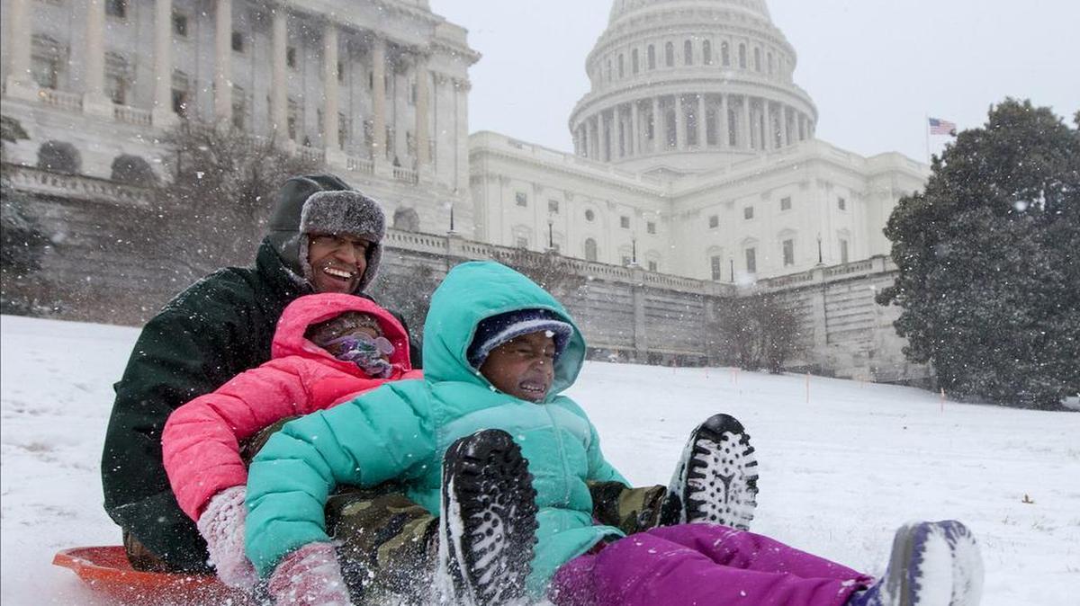 Bashon Mann and his children sled down a hill at the Capitol as snow falls in Washington, Tuesday, Jan. 21, 2014. A provision in a spending bill that Congress will vote on this week would lift a ban on sledding on the Capitol grounds.