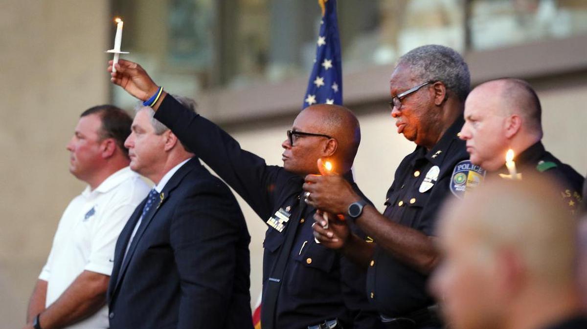 Dallas police chief David Brown, center, and Dallas Area Rapid Transit Police Chief J.D. Spiller, center right, hold lit candles up high during a ceremony in front of City Hall honoring their fallen officers, Monday, July 11, 2016, in Dallas.