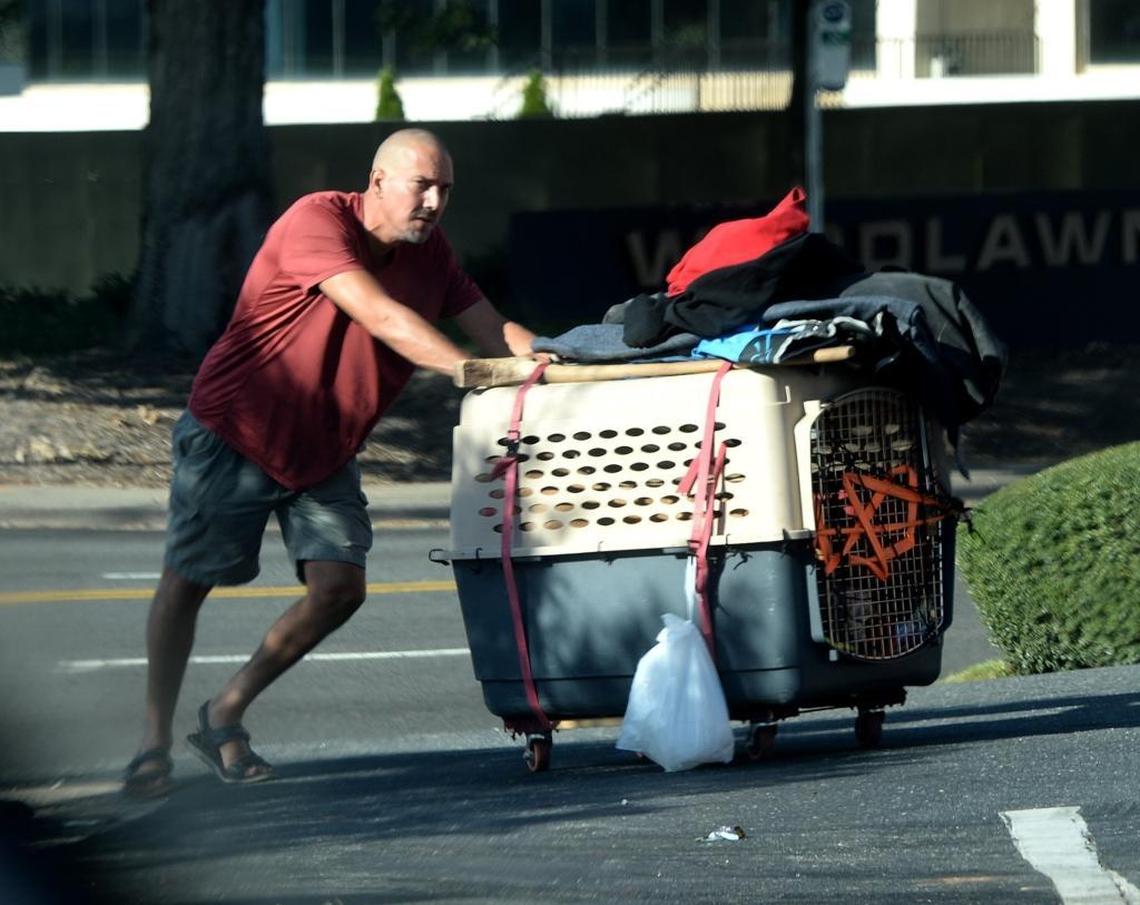 Alan Lord, who is homeless, pushes a crate containing his Lab, Levi, and all their belongings, along Woodlawn Road in October in Charlotte, North Carolina.