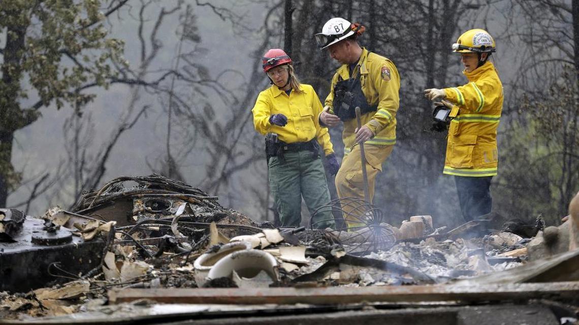 
Firefighter Sean Norman, center, and search dog handlers Mary Cablk, left, and Lynne Engelbert look over the remains of a home in the Anderson Springs area of a man missing following a wildfire days earlier Wednesday, Sept. 16, 2015, near Middletown, Calif.
