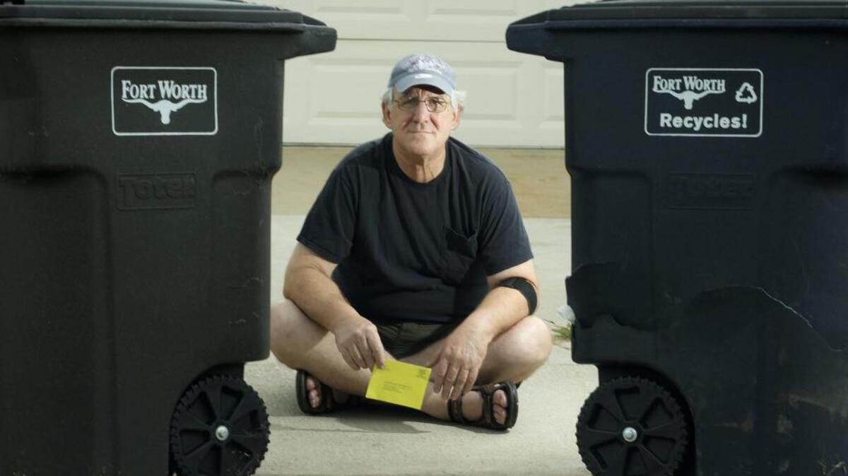 Robert Damora holds a notice alerting him that a warrant has been issued for his arrest stemming from a citation he’d been issued for violating trash cart rules at his home in north Fort Worth.