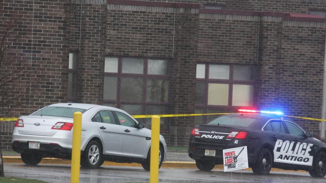 Two Antigo police department vehicles sit in front of the entrance to Antigo High School, Sunday, April 24, 2016, where an 18-year-old gunman opened fire late Saturday outside of a prom at the school.