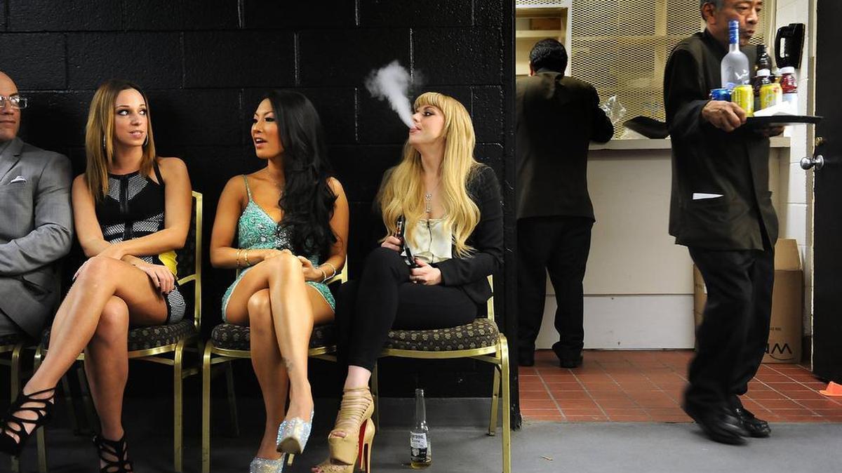Porn stars, from left, Jada Stevens, Asa Akira and Lexi Belle relax back stage as a server delivers drinks during the XBiz adult film awards at the Century Plaza hotel in Century City, Calif., Jan. 24, 2014.