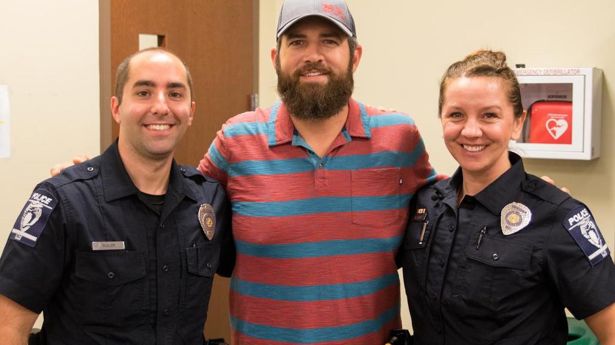 Officer Lawrence Guiler, John Ogburn and Officer Nikolina Bajic pose for a photo together at CMPD’s Providence Team Office on Tuesday. The officers saved Ogburn’s life by helping to perform CPR for more than 30 minutes after he collapsed into cardiac arrest on the floor of a Cotswold restaurant on June 26.