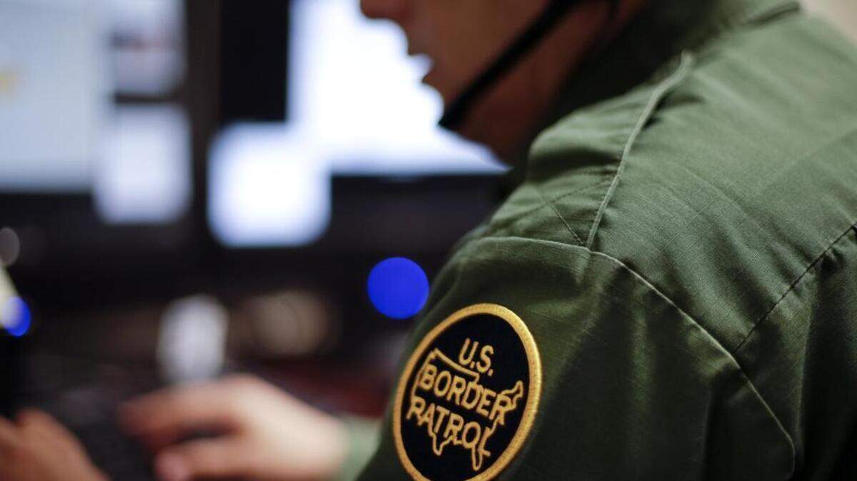 A Border Patrol agent uses a headset and computer to conduct a long distance interview by video from a facility in San Diego.