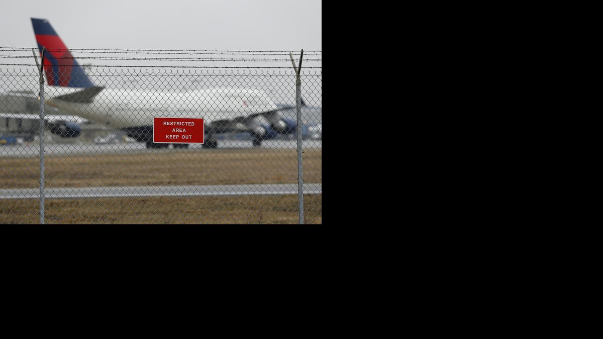 
A sign is shown posted on a perimeter fence near Delta 747 aircraft taxiing at the Detroit Metropolitan Airport in Romulus, Mich., Thursday, April 9, 2015. The security fences and perimeter gates at Detroit Metropolitan Airport have been breached four times in the past two years, an Associated Press investigation shows. Nationally, at least 268 such breaches occurred at 31 major U.S. airports since the start of 2004. 
