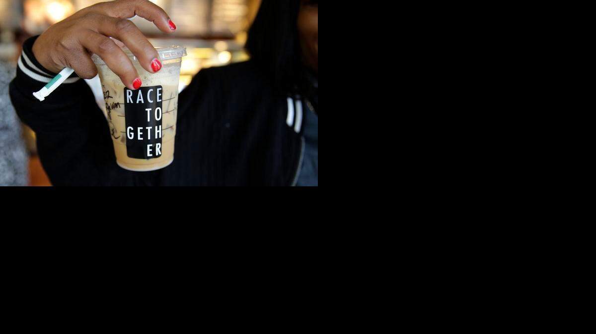 
Larenda Myres holds an iced coffee drink with a "Race Together" sticker on it at a Starbucks store in Seattle, Wednesday, March 18, 2015. Starbucks CEO Howard Schultz announced earlier in the day at the company's annual shareholder meeting that participating baristas at stores in the U.S. will be putting the stickers on cups and also writing the words "#RaceTogether" for customers in an effort to raise awareness and discussion of race relations. 
