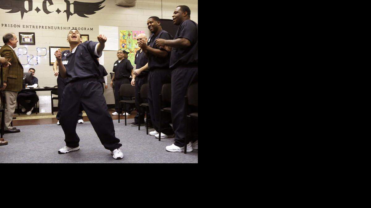 
In this photo taken Dec. 12, 2014, prison inmate Nicholas Paz, center, dances down a a line of his classmates in the Prison Entrepreneurship Program, or PEP, right, and program sponsors, in Cleveland, Texas. The rigorous program teaches inmates how to finance a business, how to market their products and how to sell themselves and their stories. PEP’s graduates have a recidivism rate of under 7 percent compared to 23 percent of the overall population in Texas. 
