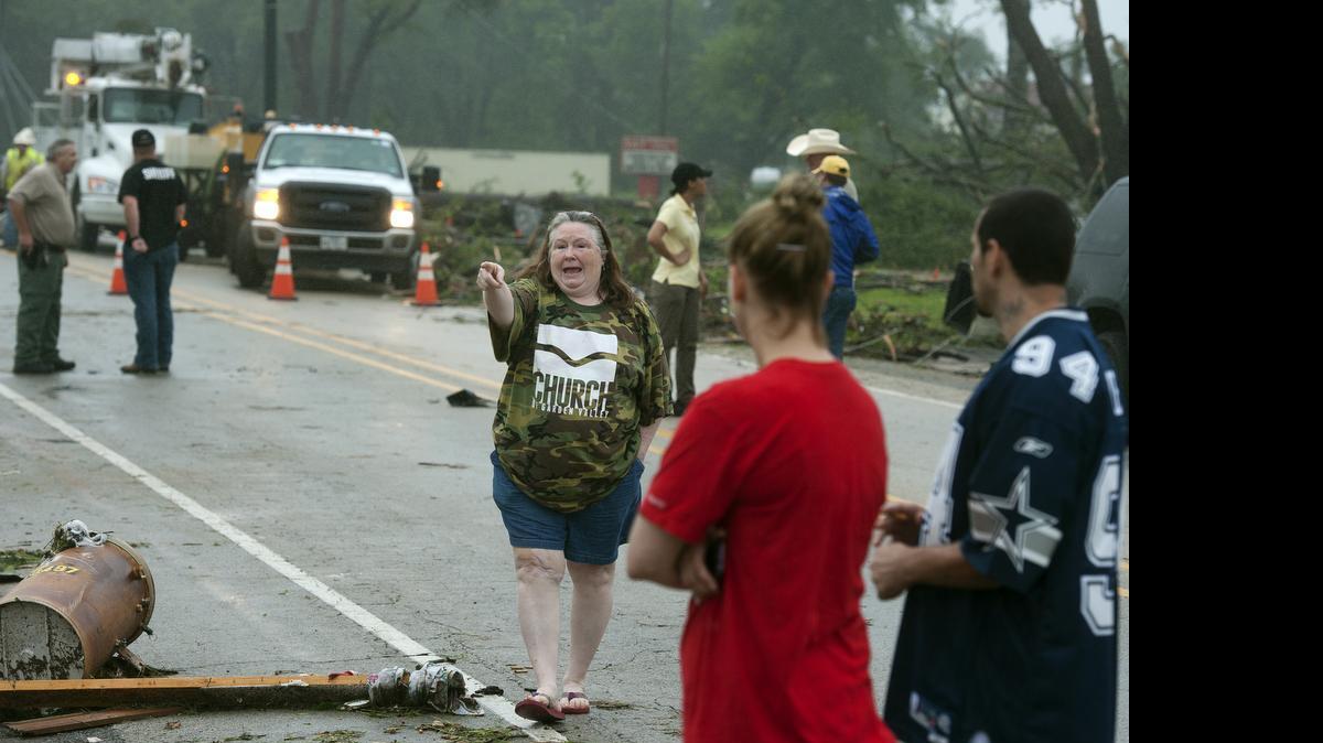 
D'Anne Smith points out the destruction of a neighbor's home as rescue and recovery personnel assess the damage in the background Monday, May 11, 2015, after at least one tornado struck the town of Van, Texas, on Sunday, May 10, 2015. Ms. Smith, who said she "road out the tornado in my closet," was one of the lucky ones as there were two reported deaths, dozens of injuries and as yet undetermined damage from the storm which destroyed about 30 percent of the community.
