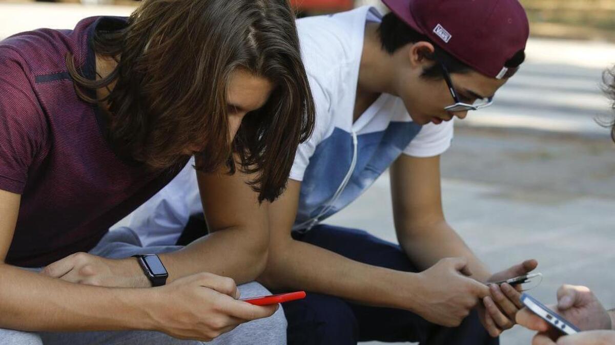 Youth check their cell phones in Sao Paulo, Brazil, Monday, May 2, 2016. (AP Photo/Andre Penner)