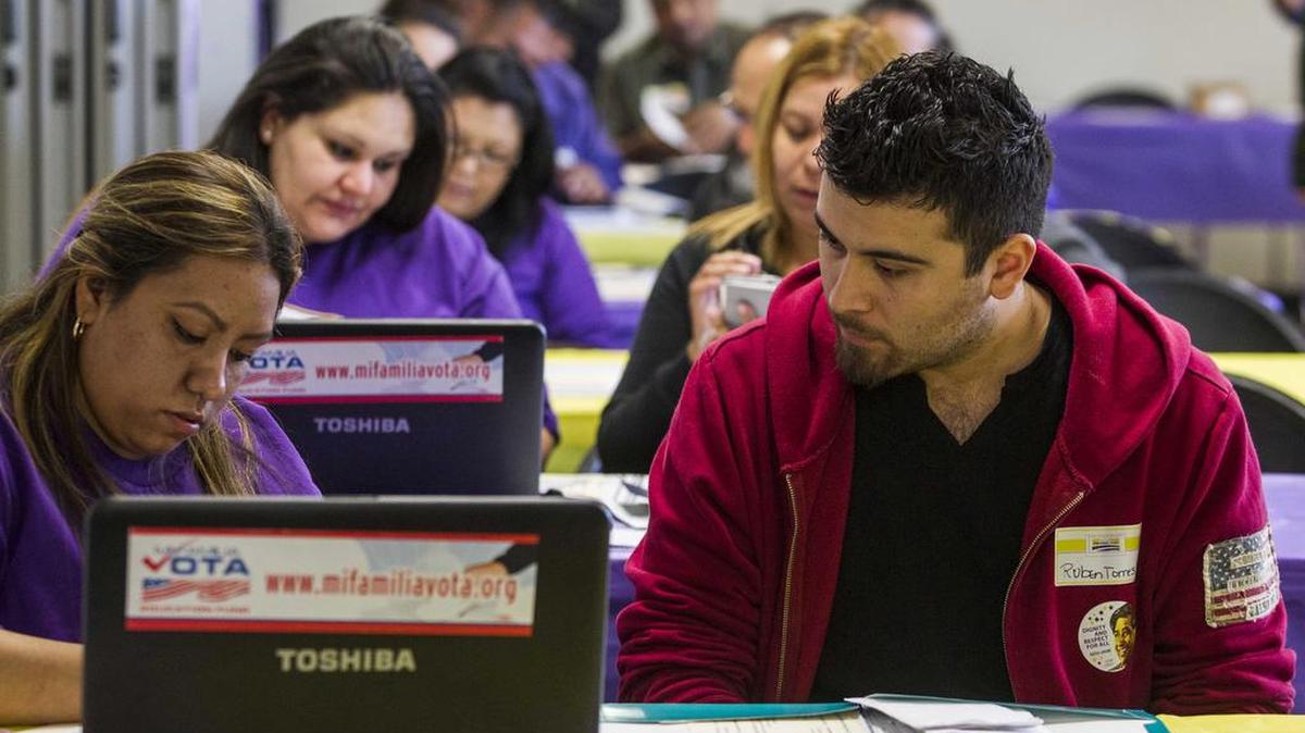 In this Monday, March 31, 2014, photo, health care representative Kathy Santana, left, assists Ruben Torres during an enrollment event Commerce, Calif.