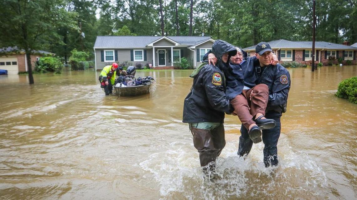 
DNR officer Brett Irvin and Lexington County, SC, Deputy Dan Rusinyak carry June Loch to dry land after she was rescued from her home in the St. Andrews area of Columbia. Residents are having to abandon their homes because of flooding coinciding with release of water from the dam. 
