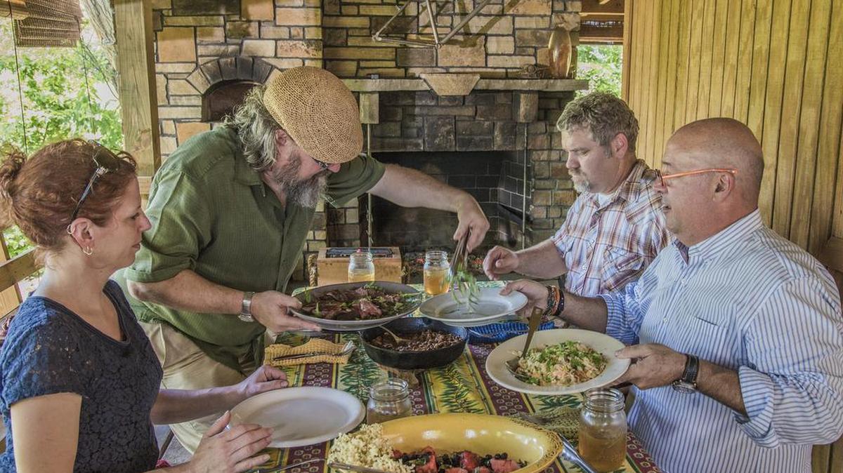 Jonathan Justus serves the woodchuck dish to his wife Camile Eklof, local sculptor Jeff Becker, who constructed the pit rotating machine, and TV host Andrew Zimmern.