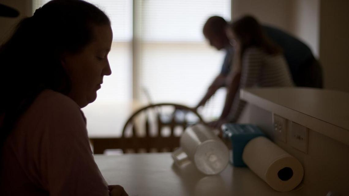 Amy Boston, left, stands in the kitchen as her daughter Alex, 14, rear right, and husband Chris looks over a computer at their home Thursday, April 26, 2012, in Acworth, Ga. Boston's family filed a libel lawsuit claiming two classmates humiliated her by using a doctored photo to set up a phony Facebook account in her name, and then stacking the page with phony comments claiming Boston was sexually active, racist and involved in drugs.