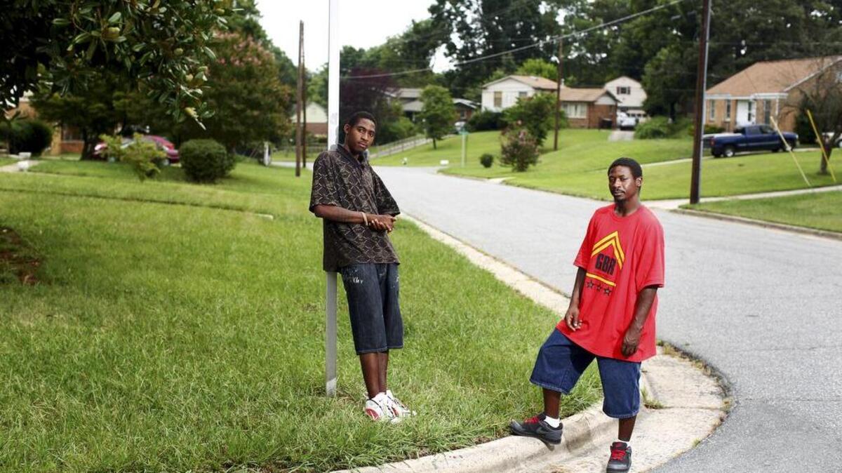 Brothers Devin, left, and Rufus Scales stand on the street corner where they were stopped while walking to the grocery store, in Greensboro, N.C., Aug. 10, 2015. In North Carolina, the state that keeps the most comprehensive statistics, Greensboro officers pulled over, searched and used force on black drivers at a disproportionate rate.
