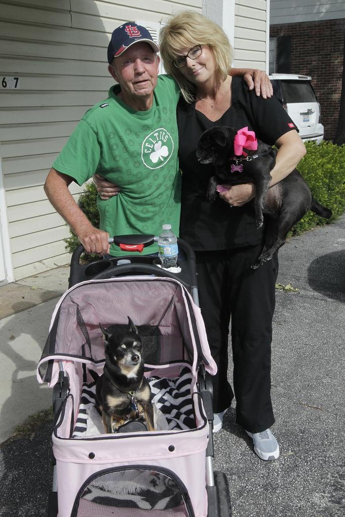 Jim Wilkerson poses with Kim Kemper, who gave him a pet stroller for his miniature pinscher, Lucky, because Lucky got tired on their daily walks and her dog, Puggy, wouldn’t ride in it.