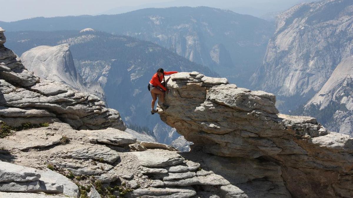 A hiker hangs out next to Clouds Rest peak in Yosemite National Park. In Yosemite, precarious granite attachments – geologists call them “exfoliations” – fall at a rate of one a week, on average.