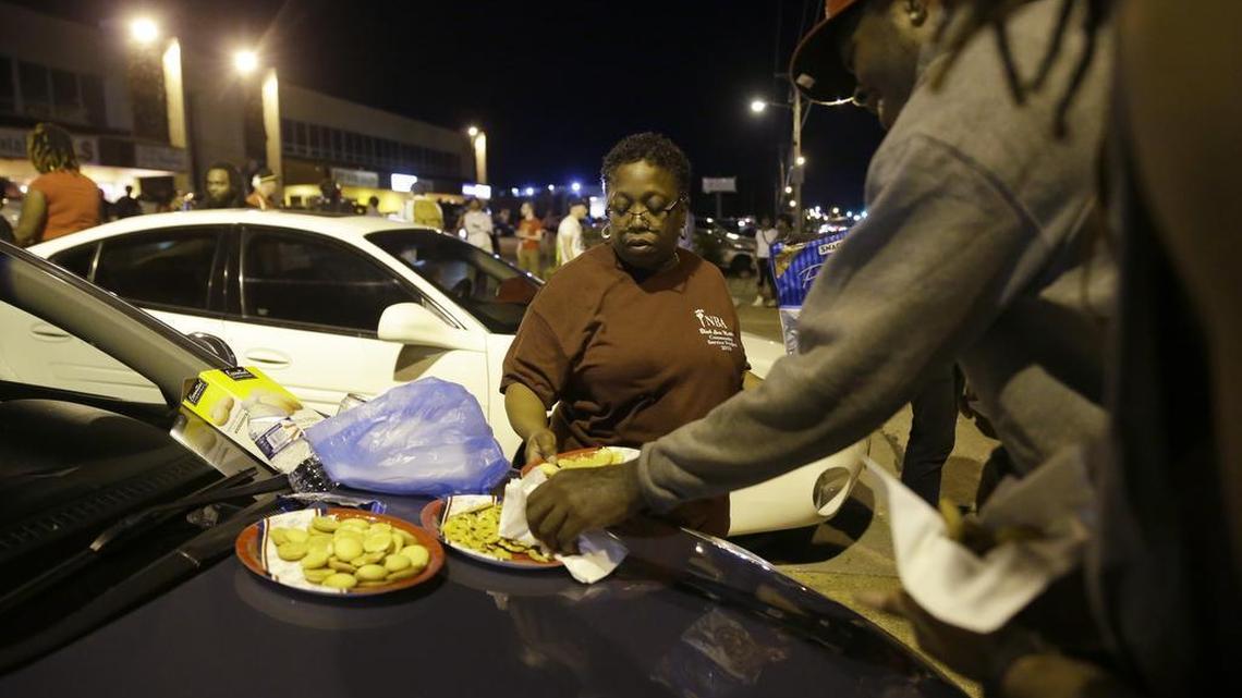 
Cat Daniels puts out snacks as smaller group of protesters gather along West Florissant Avenue in Ferguson, Mo., Tuesday. The St. Louis suburb has seen demonstrations for days marking the anniversary of the death of 18-year-old Michael Brown, whose shooting death by a Ferguson police officer sparked a national "Black Lives Matter" movement. Tuesday was the fifth consecutive night a crowd gathered on West Florissant.
