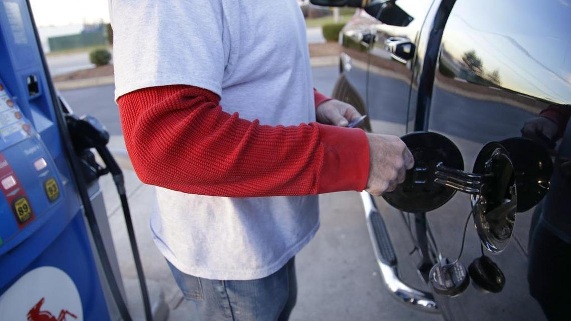 A customers opens the fuel door on his pickup truck before pumping at a gas station Monday, Dec. 7, 2015, in Pembroke, Mass.