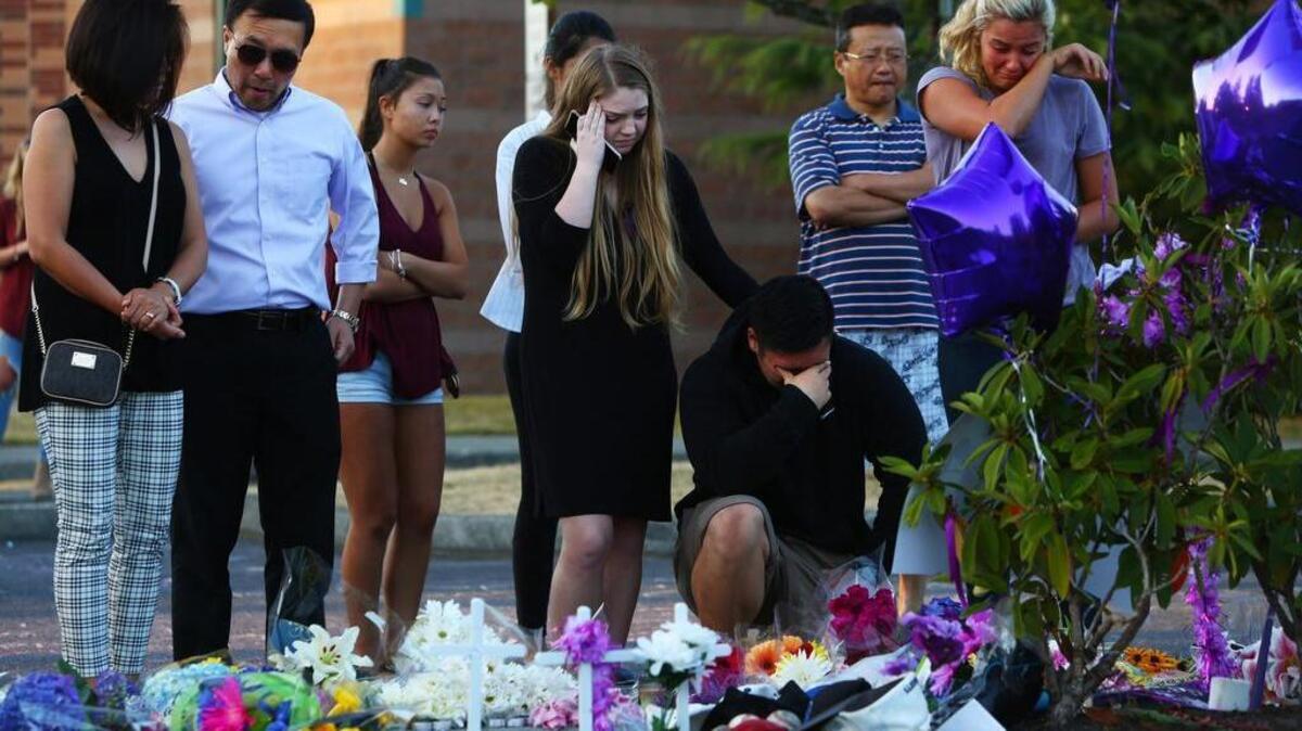 People mourn Sunday, July 31, 2016, at a memorial in the parking lot of Kamiak High School in in Mukilteo, Wash.,after a community vigil for the victims of a shooting that occurred early Saturday morning at a house in Mukilteo, killing three teenagers and wounding one.
