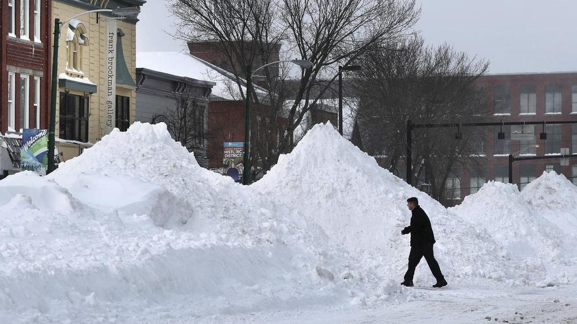 A man crosses Maine Street where snow has been piled high during a blizzard, Monday, Feb. 13, 2017, in Brunswick, Maine. A fluffy snow up to two-feet deep blanketed parts of the Northeast, just days after the biggest storm of the season dumped up to 19 inches of snow on the region.