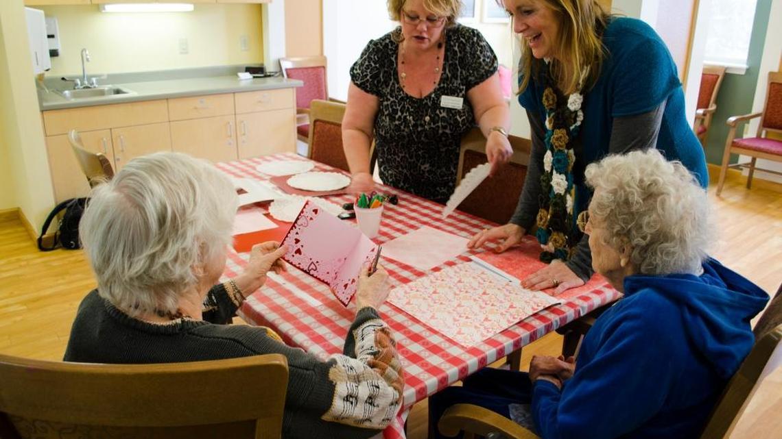 Memory-care activity leaders LeAnn Johnson and Julie Klos, center, help residents of Spring Creek in Bellingham make paper valentines on Jan. 23, 2016.