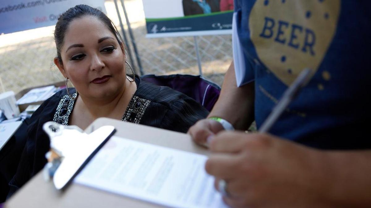 Dimas Alfaro signs up for marketplace coverage with Amanda Rodriguez, Site Supervisor for Cognosante in the Dallas-Fort Worth area, at the 2nd Annual Texas Latino Gay Pride Festival at Reverchon Park in Dallas, Texas, on Oct. 10, 2015. On Tuesday, Humana announced it would no longer offer marketplace coverage in 2018.