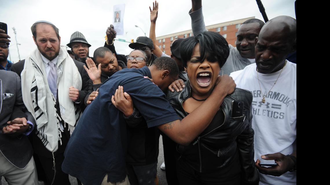 
Rev. Pamela Coleman, right, prays with Baltimore residents at the corner of West North Avenue and Pennsylvania Avenue on May 1, 2015 after charges were filed against six Baltimore police officers in the death of Freddie Gray in Baltimore, Md. 
