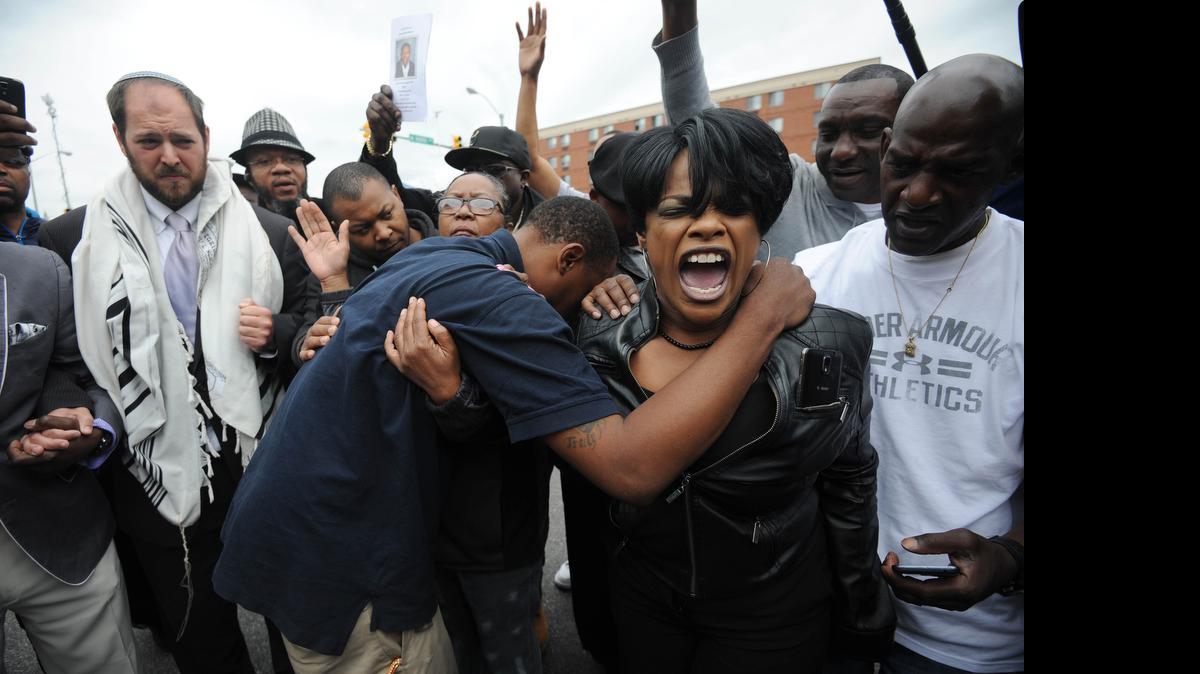 
Rev. Pamela Coleman, right, prays with Baltimore residents at the corner of West North Avenue and Pennsylvania Avenue on May 1, 2015 after charges were filed against six Baltimore police officers in the death of Freddie Gray in Baltimore, Md. 
