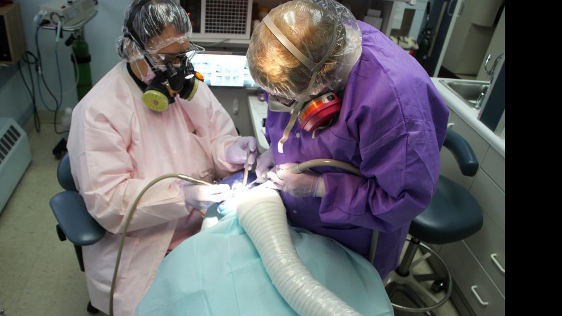 Scranton, Pa., mercury-free dentist Dr. Blanche Grube and her assistant remove a mercury/"silver filling" from a patient. All three are draped and covered for protection from mercury vapor and particles.