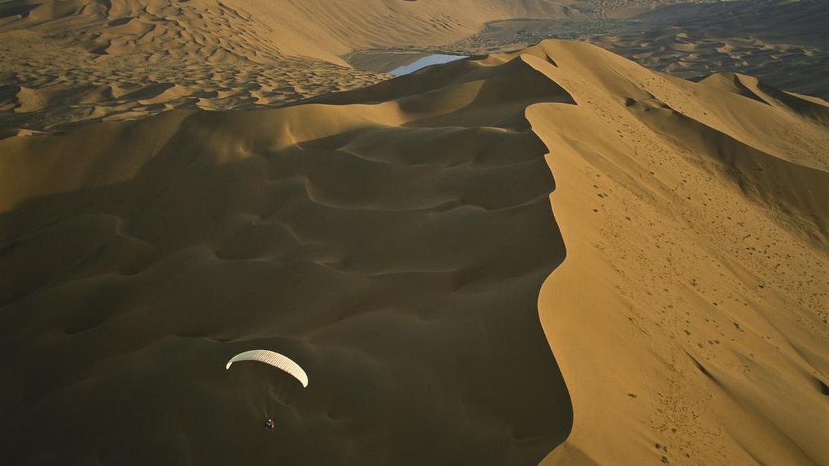 
Alain Arnoux flying a motorized paraglider over the Badain Jaran dune field in a photograph from "Desert Air" by George Steinmetz. A man flying a motorized paraglider says the wind blew him over a Los Angeles-area jail, resulting in a chase that was unusual even by LA standards. 
