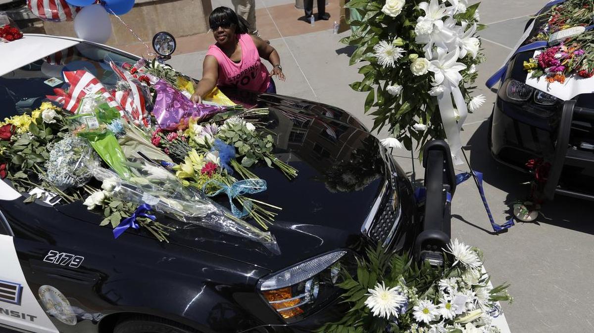 Cynthia Ware places flowers on a make-shift memorial at the Dallas police headquarters, Friday, July 8, 2016, in Dallas. Five police officers are dead and several injured following a shooting in downtown Dallas Thursday night.
