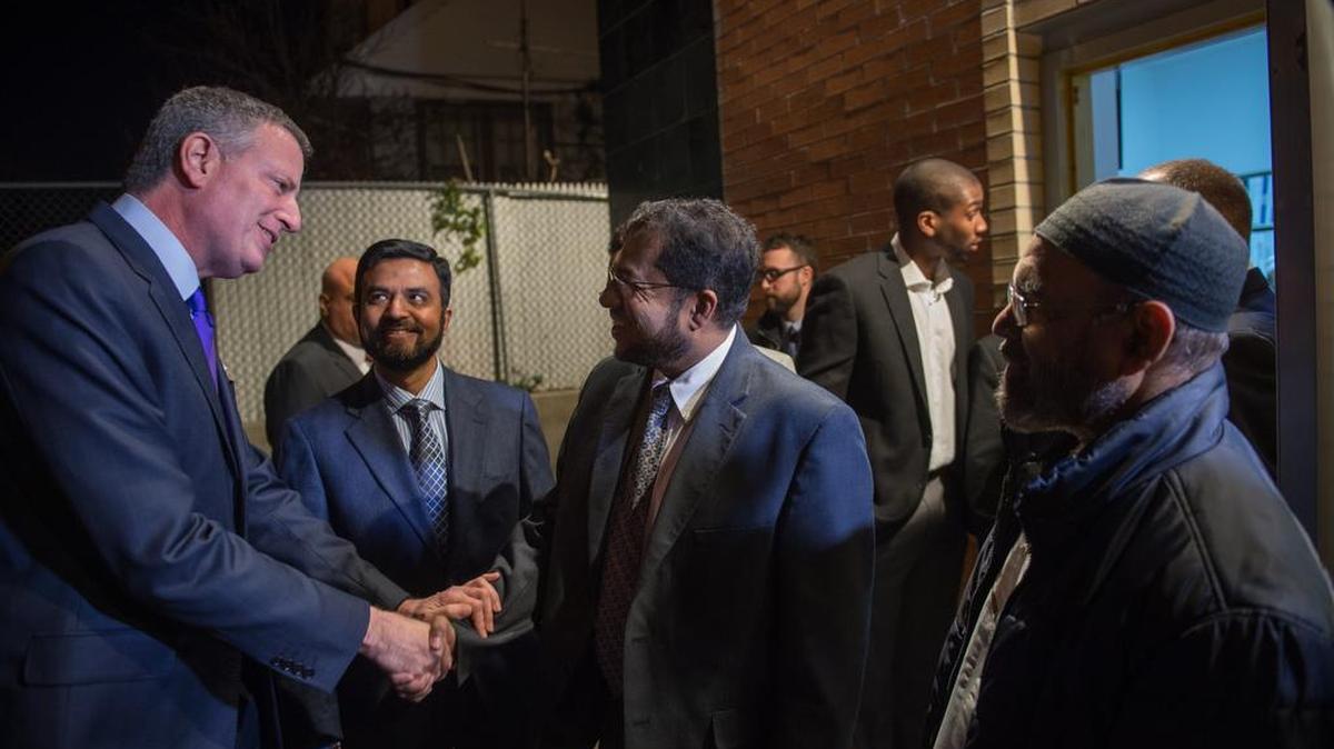 New York City Mayor Bill de Blasio, left, arrives to speak Friday at the Jamaica Muslim Center, where he welcomed a dozen Syrian refugees bound for Texas to New York City.