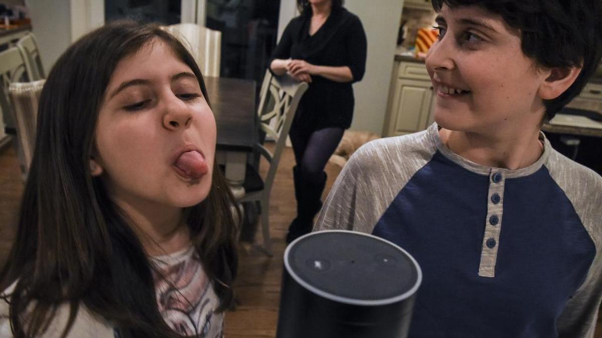 "We like to ask her a lot of really random things," said Emerson Labovich, left, a fifth-grader in Bethesda, Md., who pesters Alexa with her older brother Asher, right. Mom Laura Labovich is in the background.